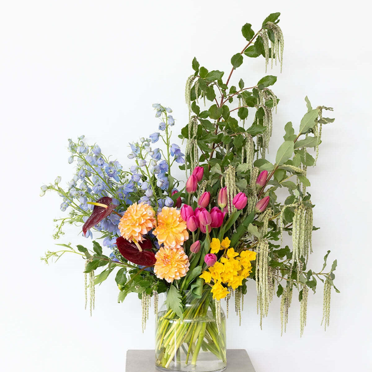 Vibrant Jewels Bouquet showcasing bright flowers in a glass vase against a simple background.