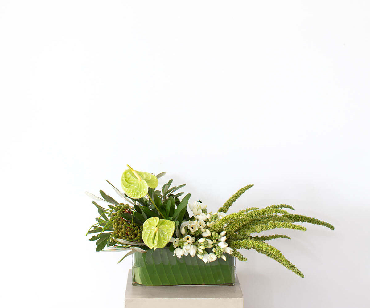 Sculptural White & Green Table Arrangement in a glass vase with lush green and white florals.